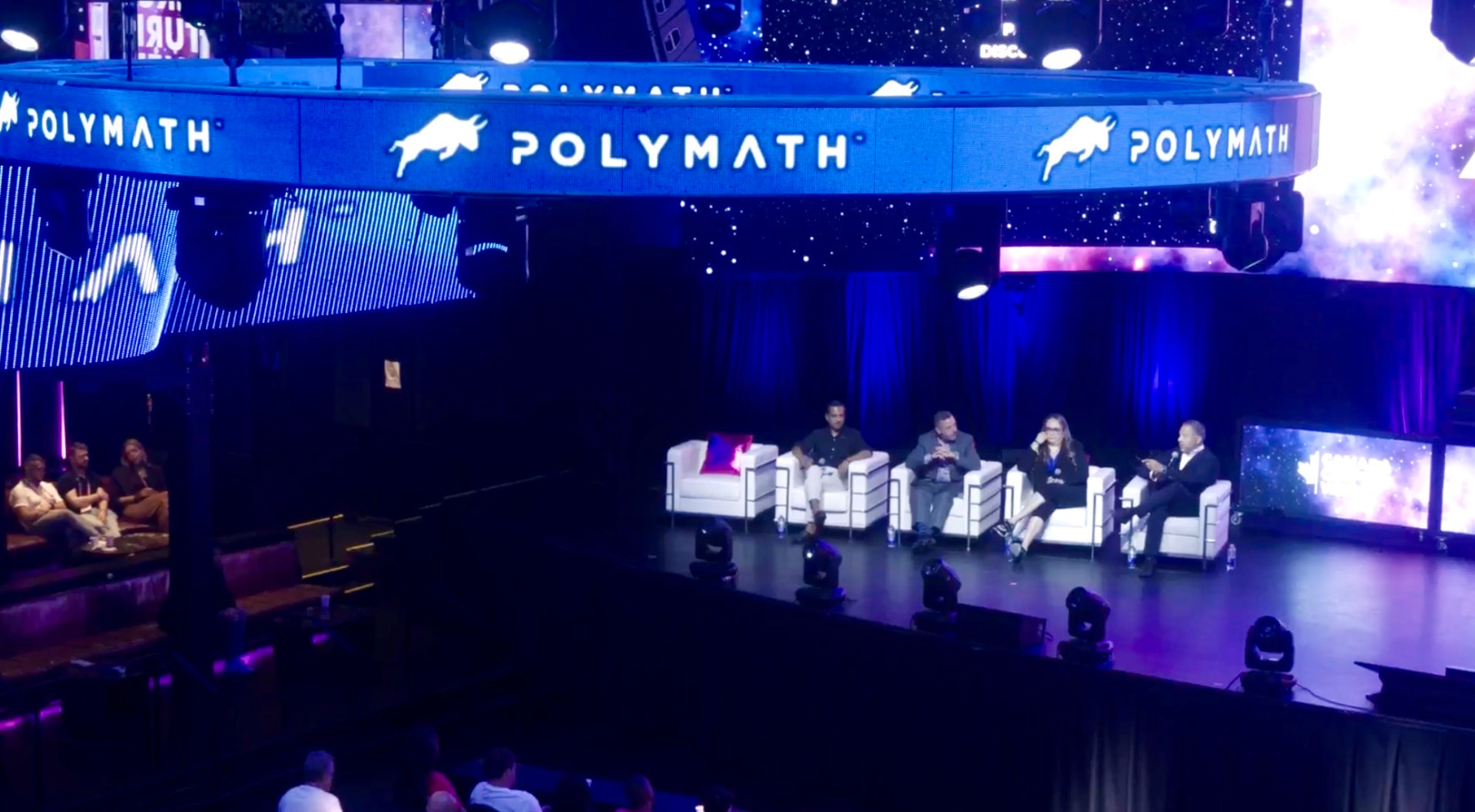 Wide view of a Polymath-branded conference stage with Natalie Hirsch seated on the panel