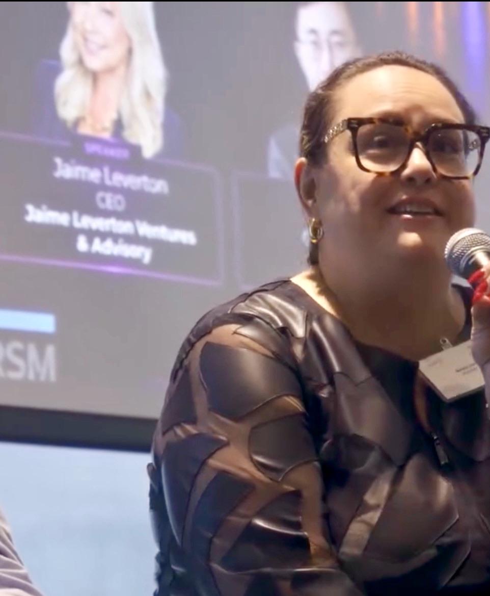 Close-up of Natalie Hirsch speaking into a handheld microphone on a panel
