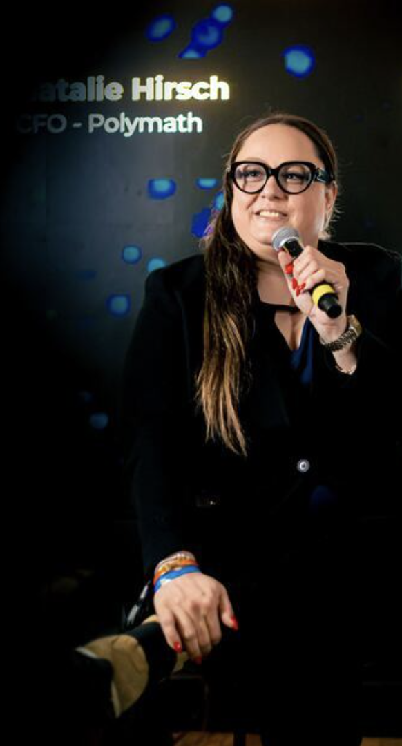 Natalie Hirsch smiling mid-sentence, microphone in hand